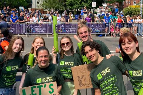 Leeds Marrow smiling in green Anthony Nolan Tshirts with cheersticks and signs at the Leeds Marathon