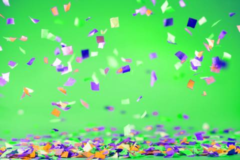 Purple, orange and green confetti falling down in front of a green background