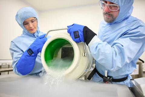 Researchers pouring a large tub of liquid nitrogen into a cryotank
