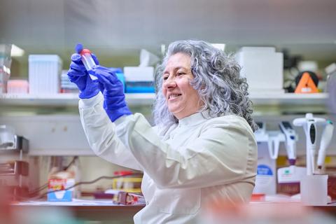 Researcher in a lab setting examining a DNA LoBind tube and smiling