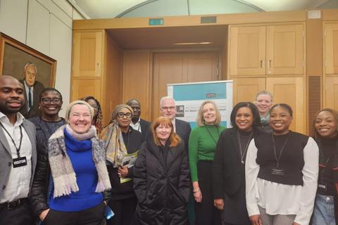 13 people smiling as a group, posed for a picture to be taken