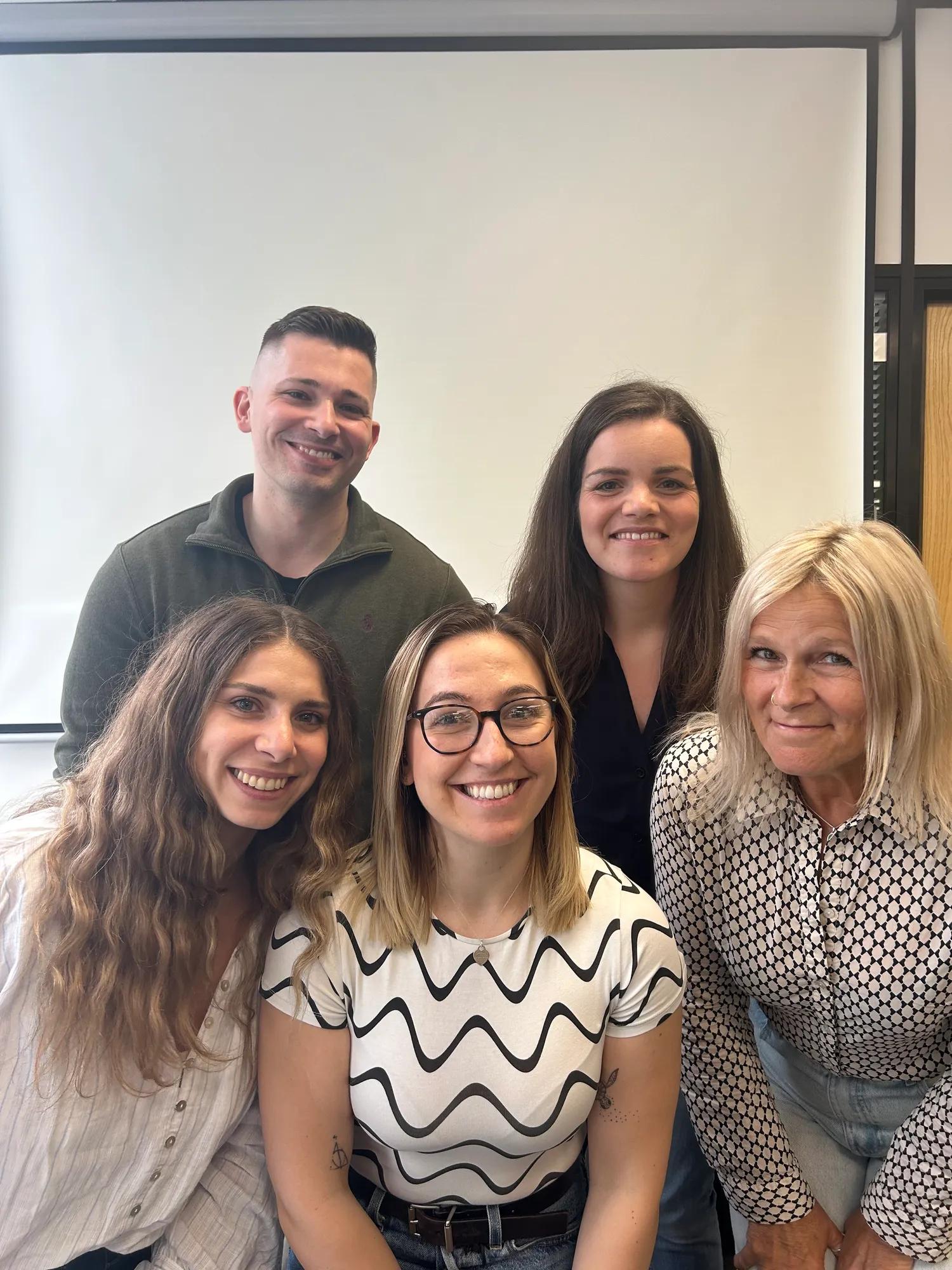 A team of five people posing for the camera