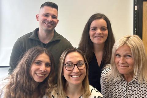 A team of five people posing for the camera