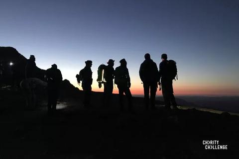 Peoples stood at the top of a mountain at sunrise