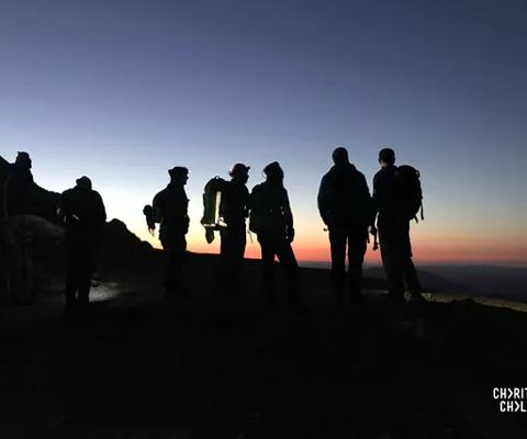 Peoples stood at the top of a mountain at sunrise