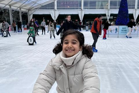 Nine-year-old Amilah pictured ice skating on a rink holding a penguin stabiliser.  