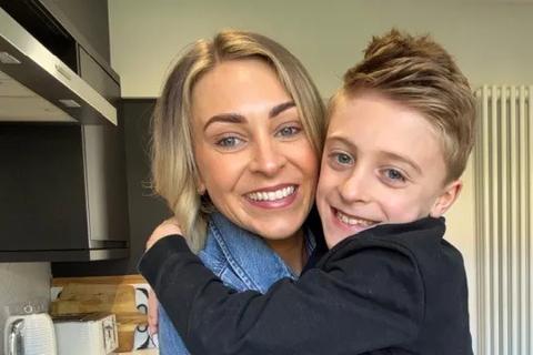 Sophie smiling at the camera and hugging her son Freddie