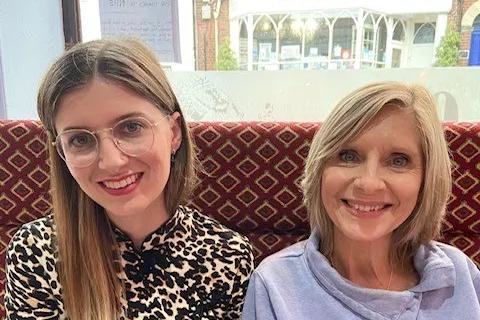 A young woman called India and her mum Amanda sat together at a restaurant table 