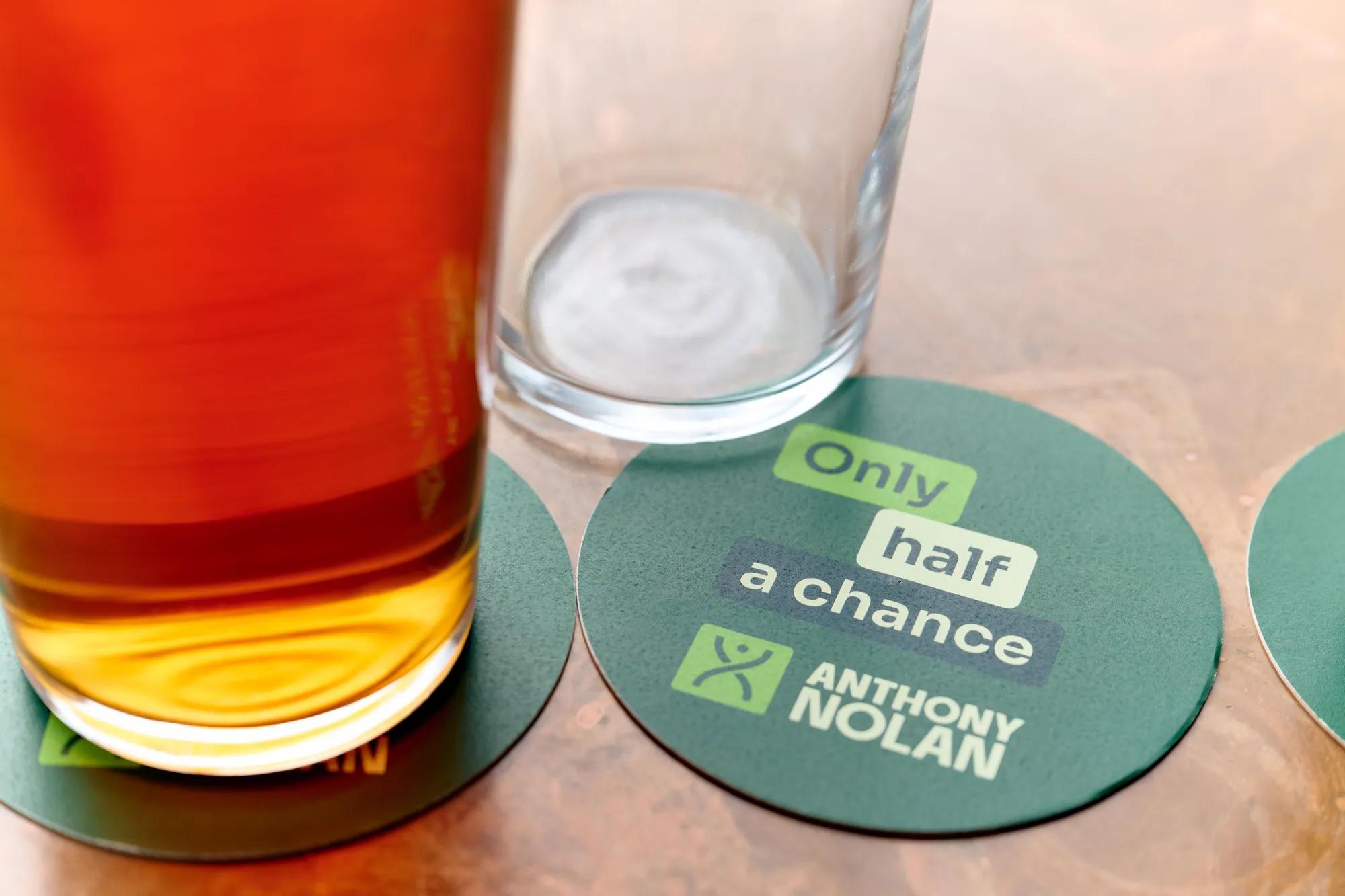 Anthony Nolan branded beer mat that reads only half a chance next to a half pint of beer