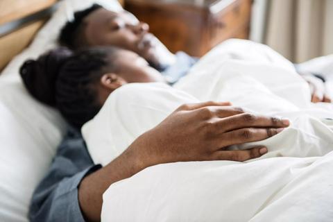 Minority ethnic couple hugging in bed