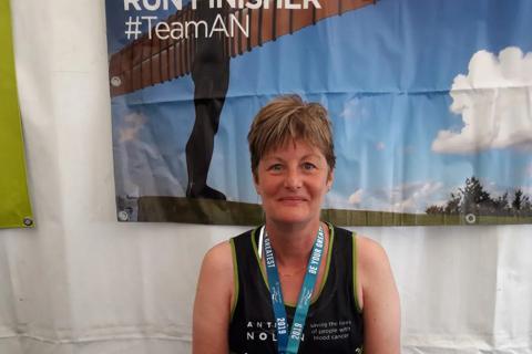 A woman wearing an Anthony Nolan running vest and medal around her neck