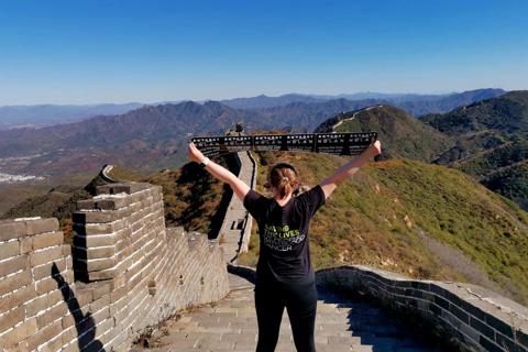 Photo of a woman with an Anthony Nolan tshirt on and banner, standing on the Great Wall of China