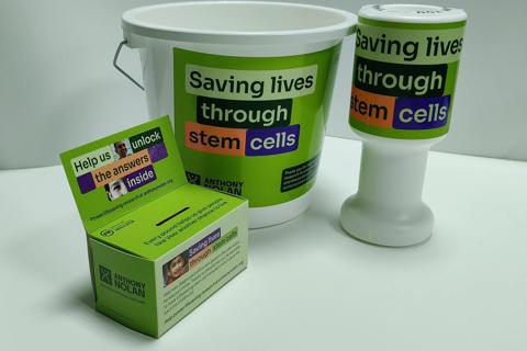 Anthony Nolan branded fundraising money collection box, bucket and pot sat on a table 