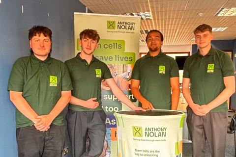 Four young male fundraisers standing around an Anthony Nolan pull-up banner and podium.