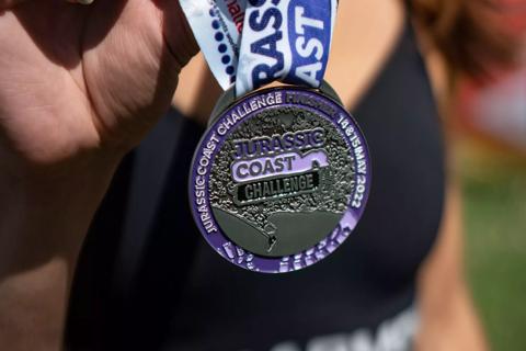 Photo of a medal which says Jurassic Coast and has a purple ribbon