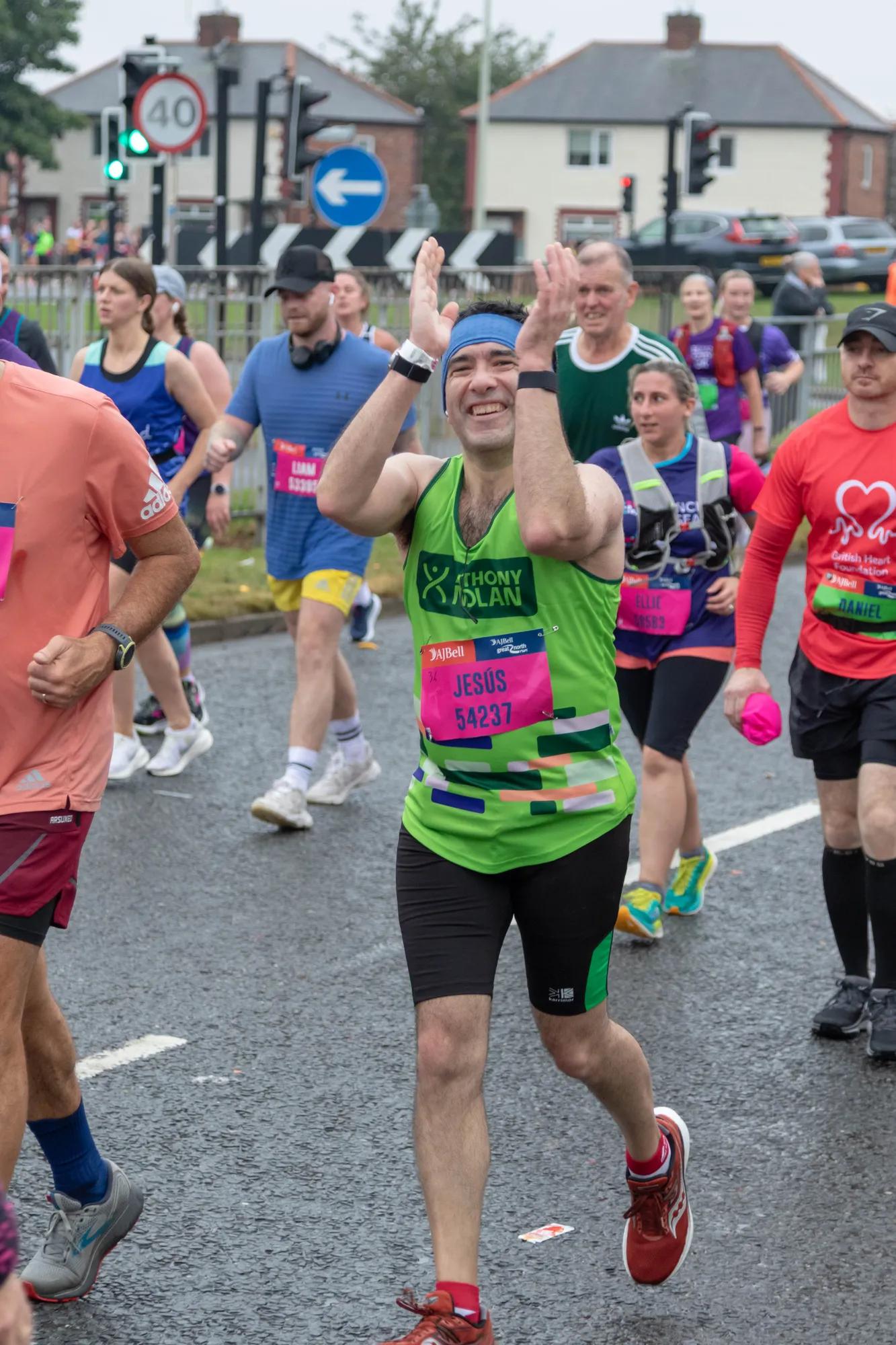 a man running with a crowd of people, he's wearing an Anthony Nolan vest and black shorts vest 