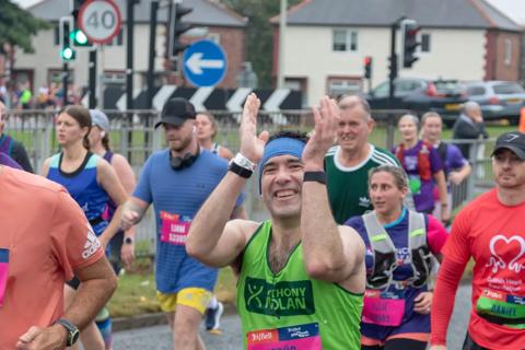 a man running with a crowd of people, he's wearing an Anthony Nolan vest and black shorts vest 