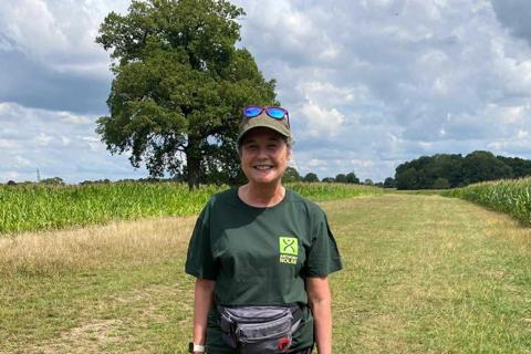 a woman in  a field with her dog, she's wearing an Anthony Nolan t-shirt and a cap