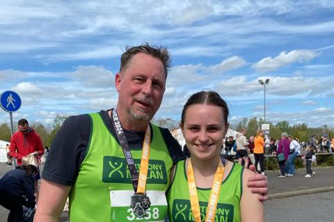 A man and woman in their green Anthony Nolan vests with medals around their neck 