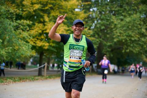 Male runner smiling at the camera, wearing Anthony Nolan green vest