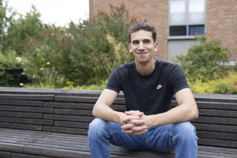 Louis Martin sat outside on a bench and smiling at the camera