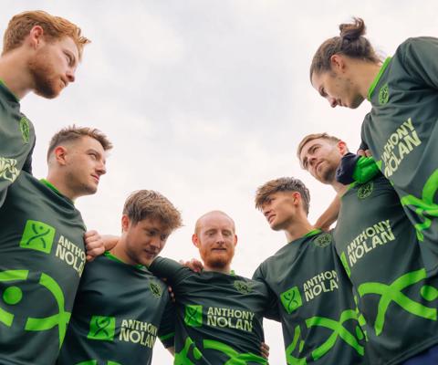 Group of people in football shirts in a huddle