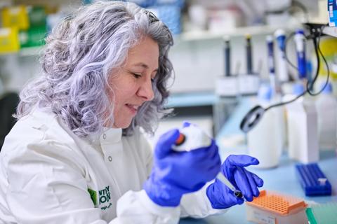 Researcher in a lab coat using a micropipette