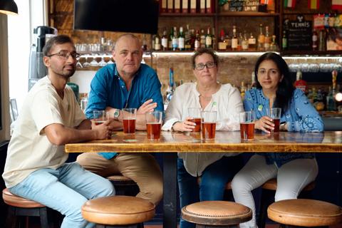 A white female patient and a south asian male and female patient sat with comedian Al Murray holding half pints of beer looking at camera