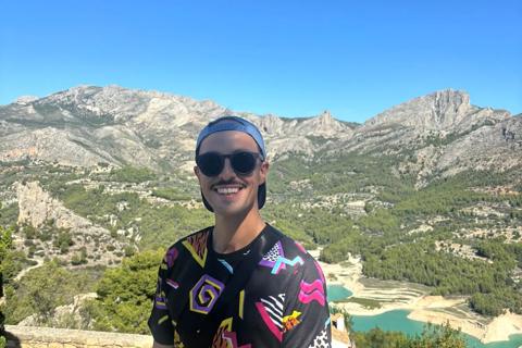 A photo of Dan on holiday, he is wearing a patterned t-shirt, bright orange shorts and sunglasses.