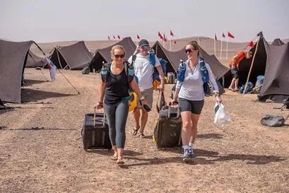 two women wheel suitcases through the desert