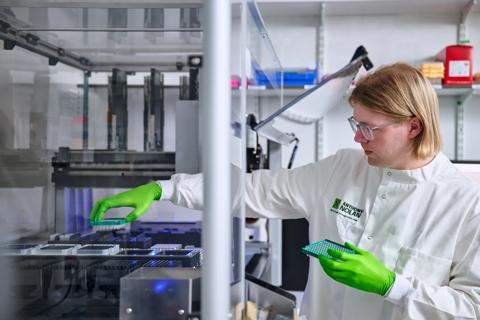 Researcher placing a tube rack into the Hamilton robot