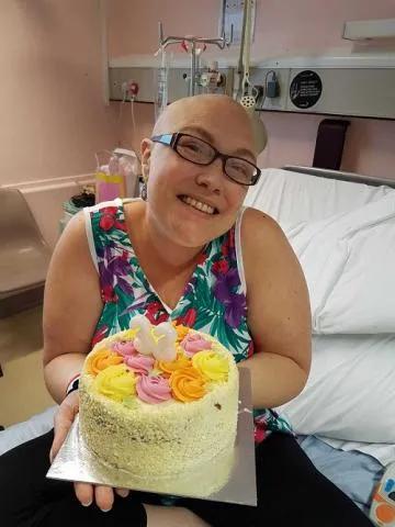 Donna sat on a hospital bed holding a cake