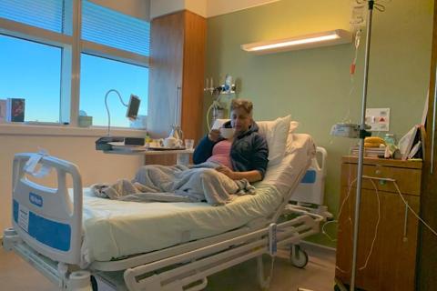 A hospital room, with a woman with shaved hair in the bed