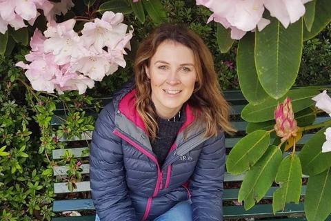 A young woman sat on a park bench, surrounded by flowers