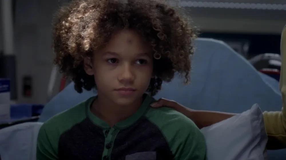 A boy sitting on a hospital bed looking apprehensive