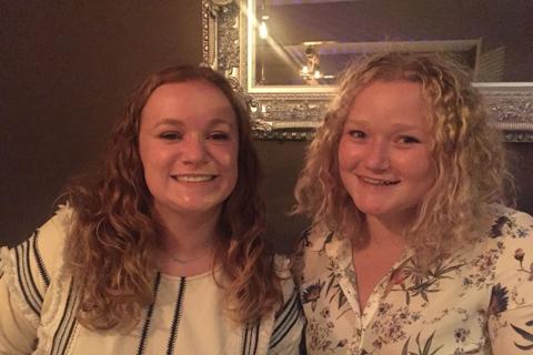 Emma, a young women with blonde curly hair, with her sister who has long curly  brown hair