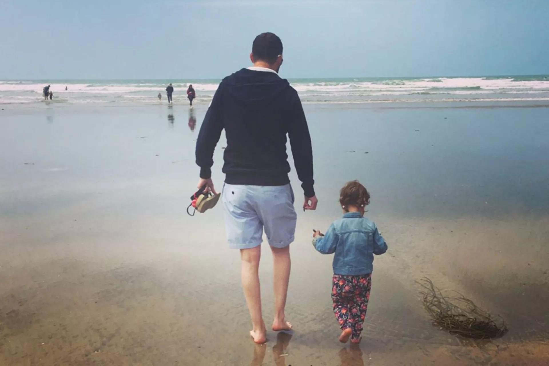 Alex, walking on the beach with his daughter
