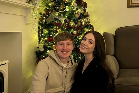 Ben (l) and Fran (r) sitting in front of a decorated Christmas tree in their living room