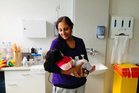 Rita in a hospital room holding her baby daughter and smiling
