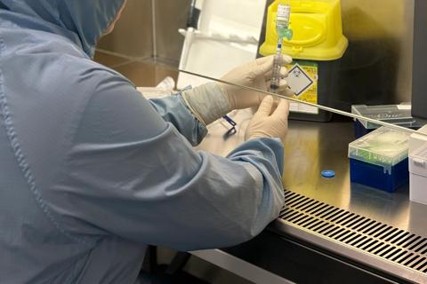 A cell therapy scientist using a syringe to extract from a vile at Nottingham Cell Therapy Centre