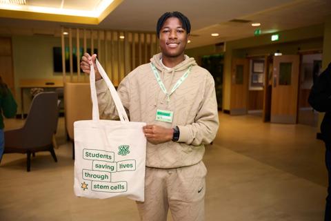 Student holding tote bag which reads 'Students saving lives through stem cells'