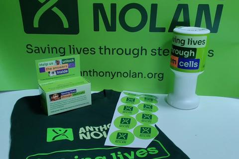 A set of Anthony Nolan branded fundraising materials including a tshirt, banner, stickers and money collection pot