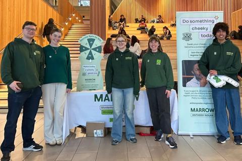A photo of five young people wearing Anthony Nolan branded jumpers and stood in front of a donor recruitment stall at Warwick University.