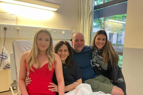 joanna sitting in her hospital bed with her husband and two teenage daughters