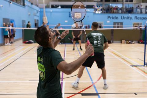 Man playing badminton with his back to the camera to show Team AN branded tshirt